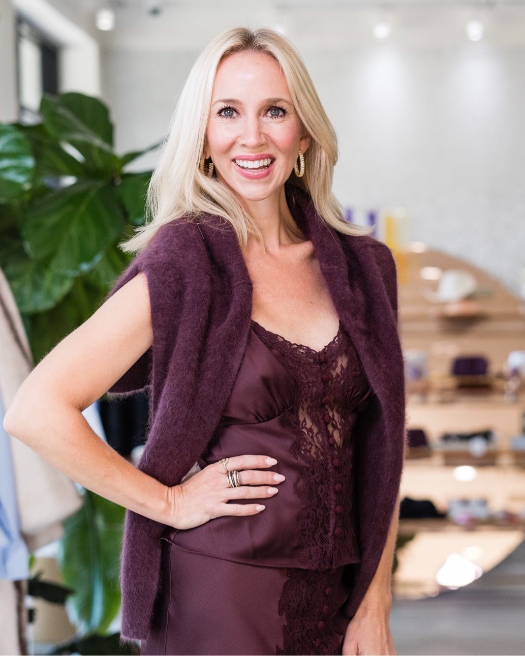 Lukka Boutique owner in a plum lace slip dress and mohair cardigan inside the store