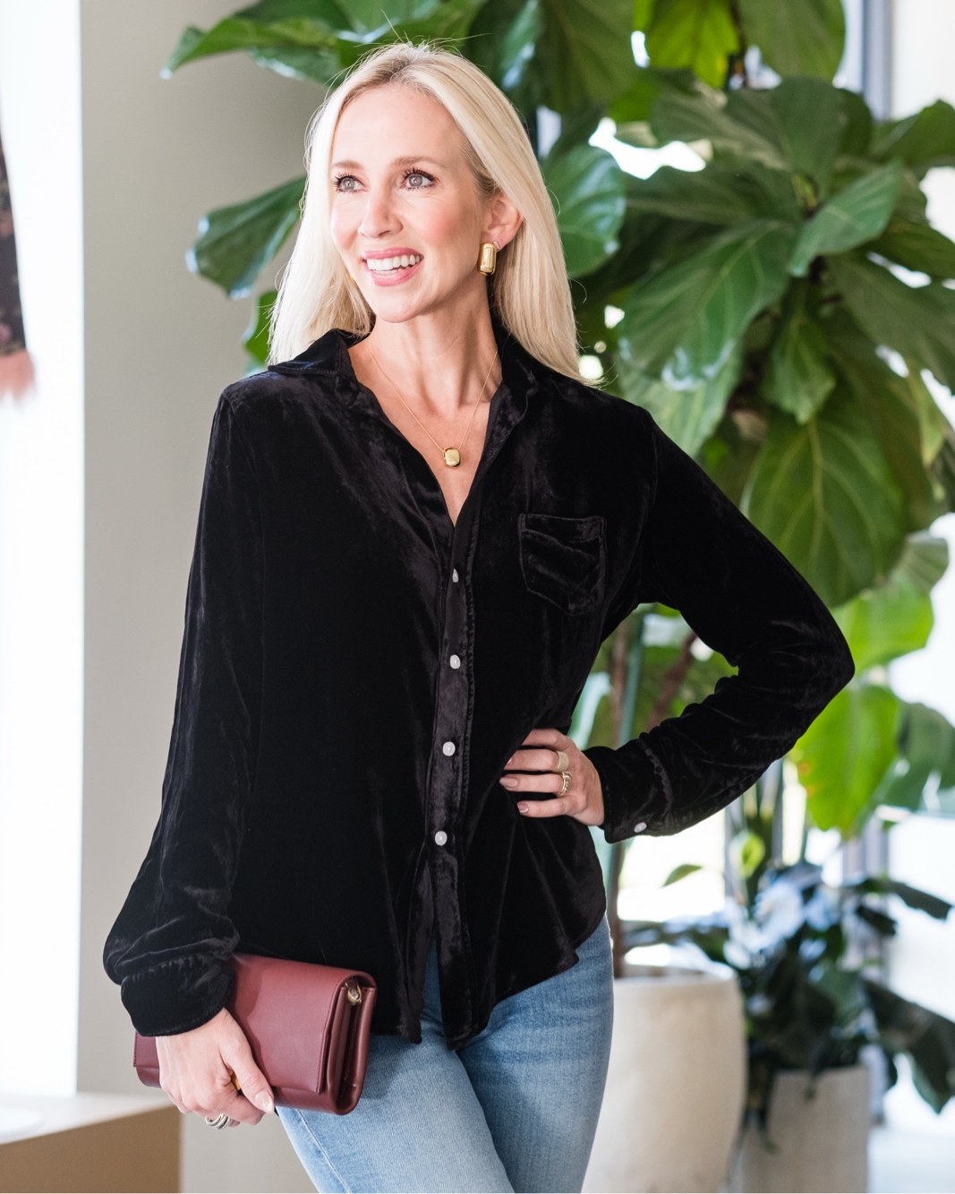 Woman in a black velvet button-up shirt and jeans inside Lukka Boutique